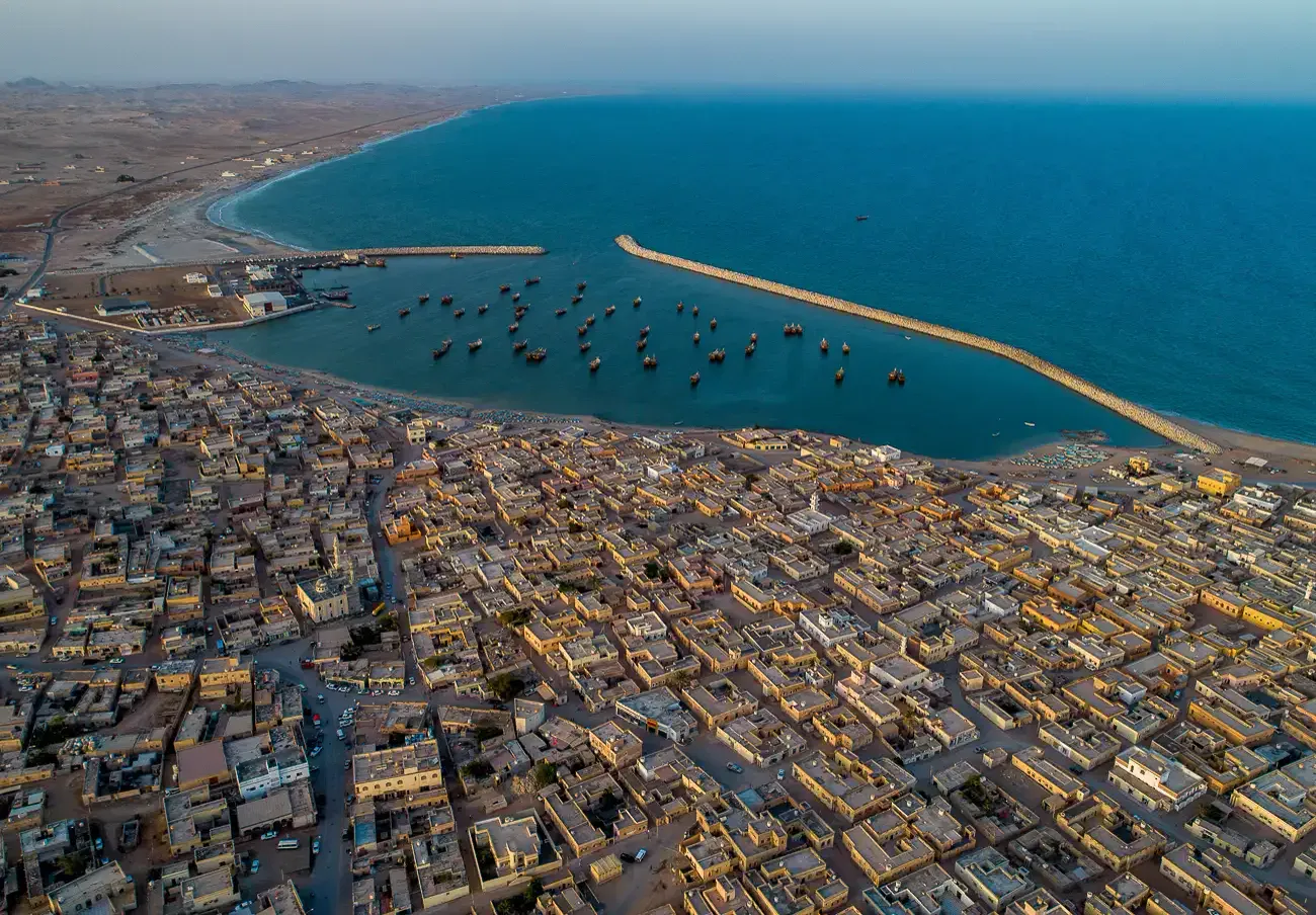 Luchtfoto van het kustdorp Al Ashkharah met zijn vissershaven vol bootjes langs de baai van de Arabische Zee