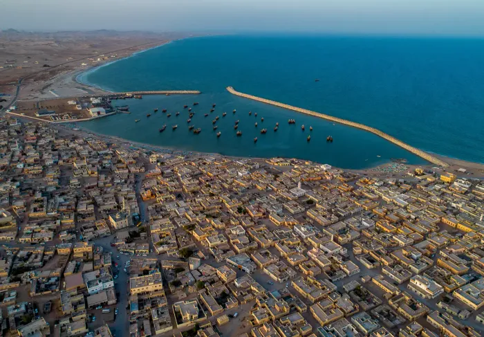 Luchtfoto van het kustdorp Al Ashkharah met zijn vissershaven vol bootjes langs de baai van de Arabische Zee