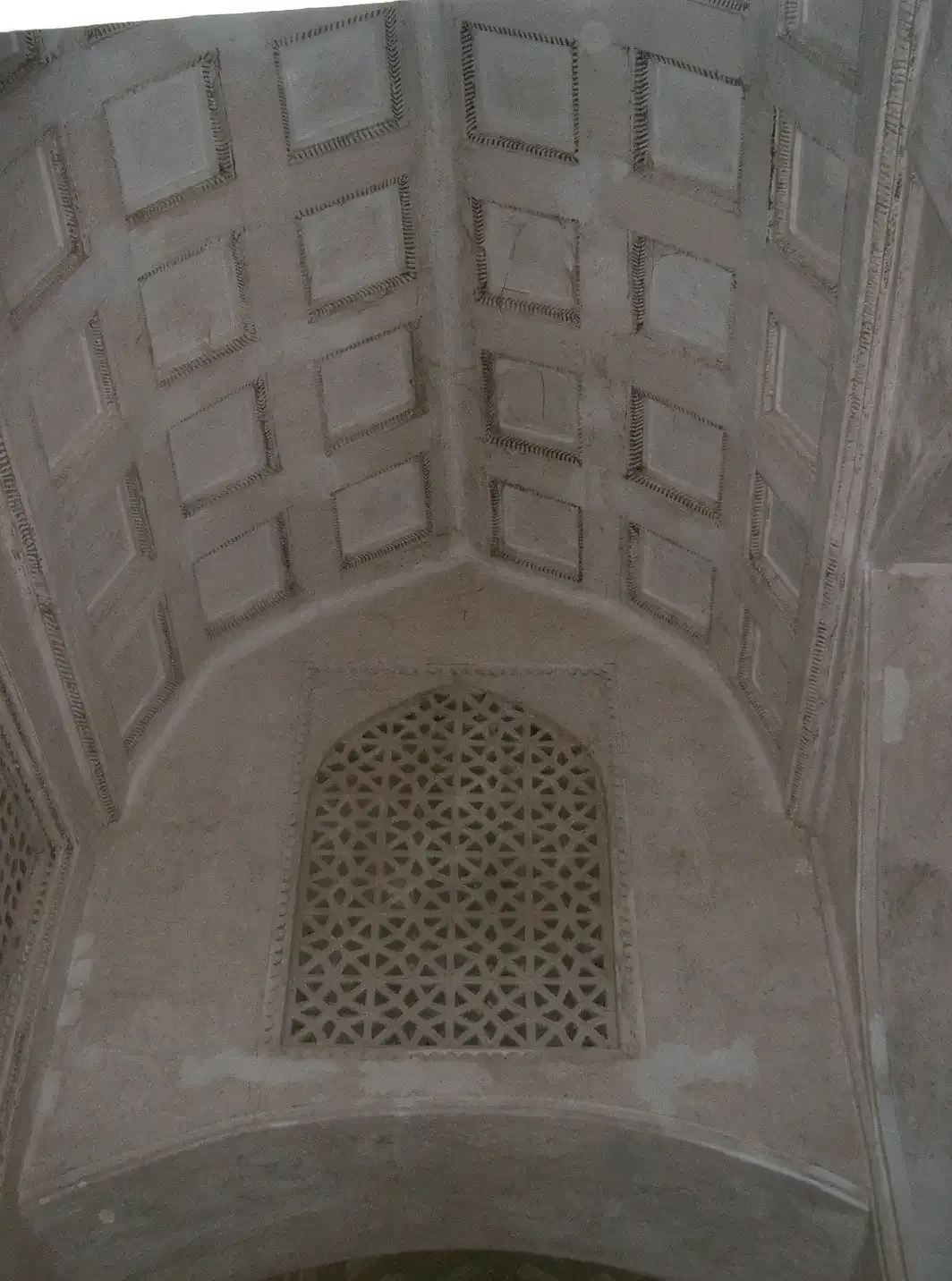 Detail van het fijne gipsstucwerk en een opengewerkt venster onder het gewelfde plafond van het Al Hazm-fort