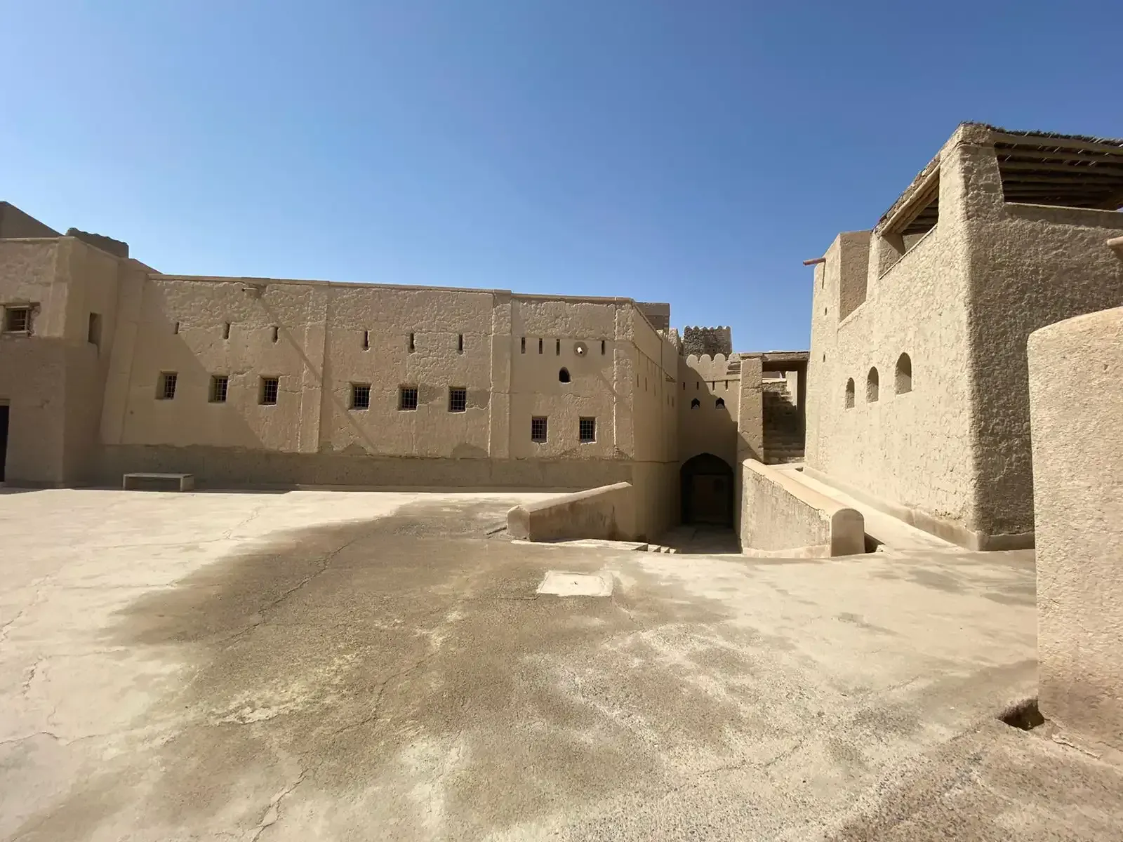 Een ruime binnenplaats in het Bahla-fort, omsloten door hoge lemen muren met kleine vensters