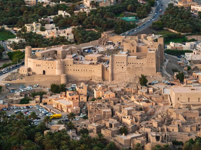 Luchtfoto van het uitgestrekte Bahla-fort op zijn heuvel, omringd door de lemen oasestad en palmtuinen