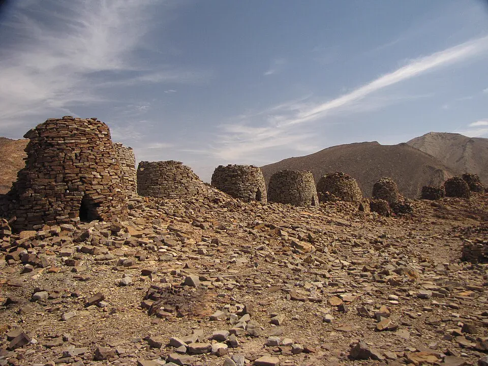 Een rij stenen beehive-tombes uit de bronstijd op een bergkam bij Al-Ayn, onder een blauwe lucht met sluierwolken