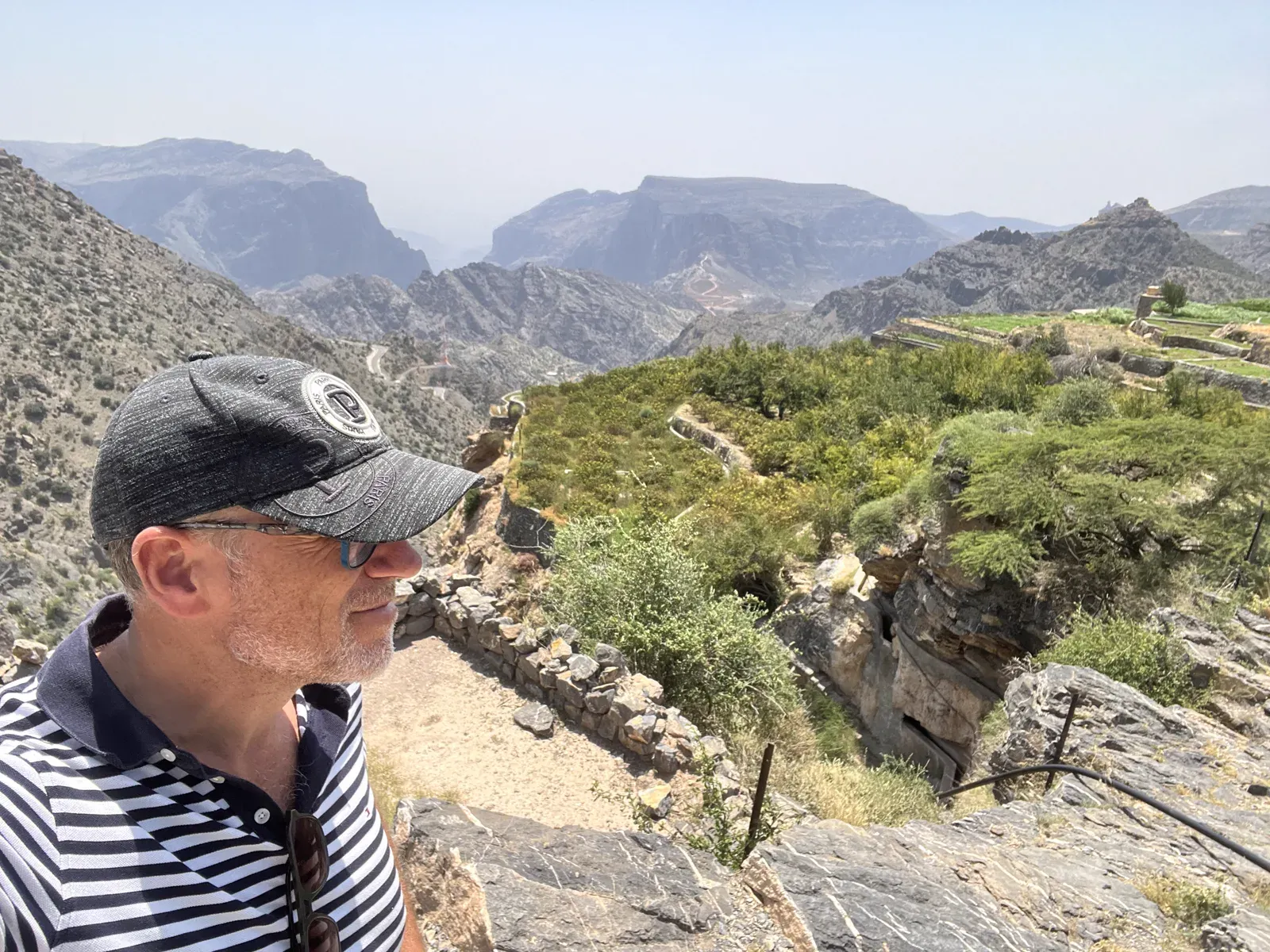 Frank kijkt uit over de groene bergterrassen en diepe kloven van het Hajar-gebergte in Oman