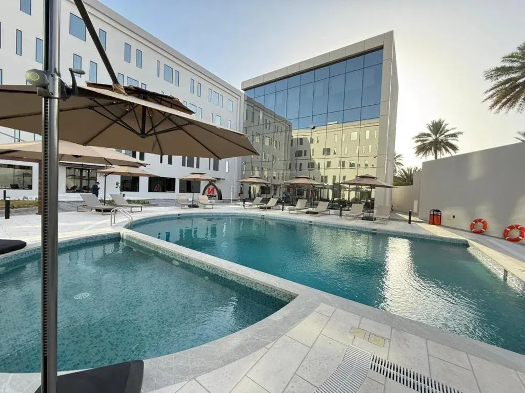 Zwembad met parasols en ligbedden bij het Swiss-Belhotel Nizwa