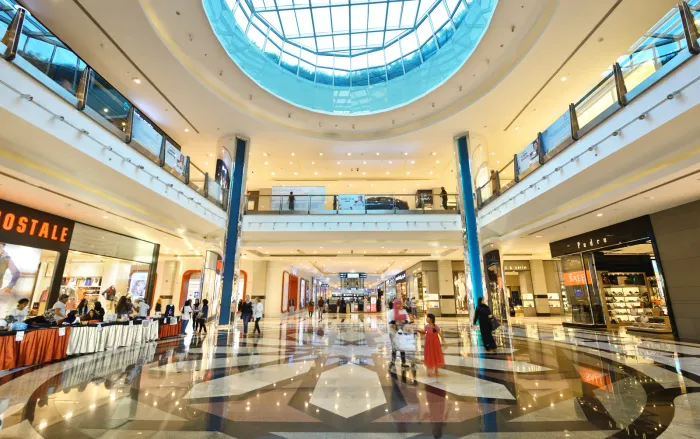 De lichte atriumhal van de Mall of Muscat met glazen koepel, marmeren vloer en winkels over meerdere verdiepingen