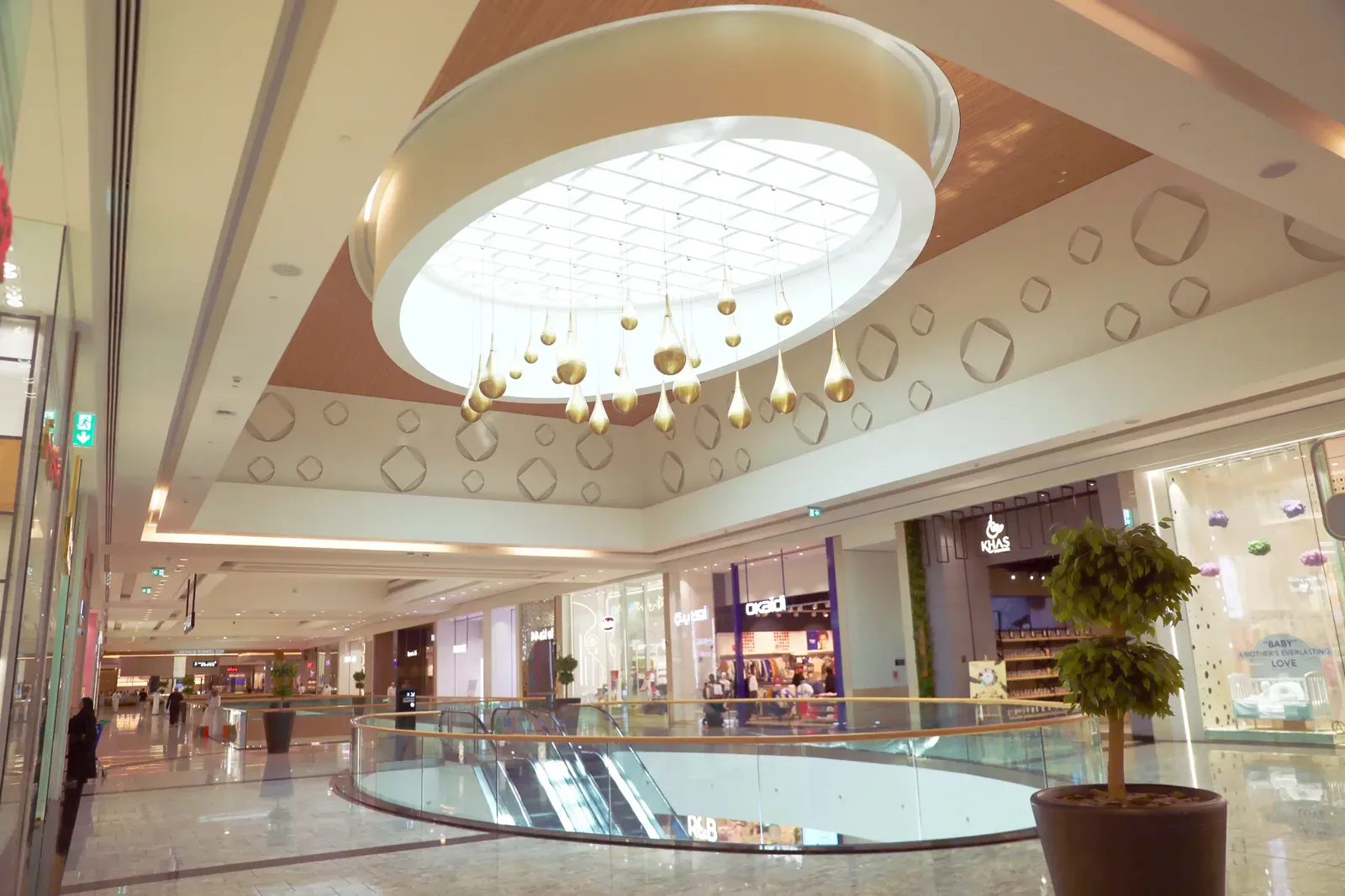 De lichte centrale hal van de Mall of Oman met een groot rond dakraam en gouden hangornamenten boven de winkelgalerij