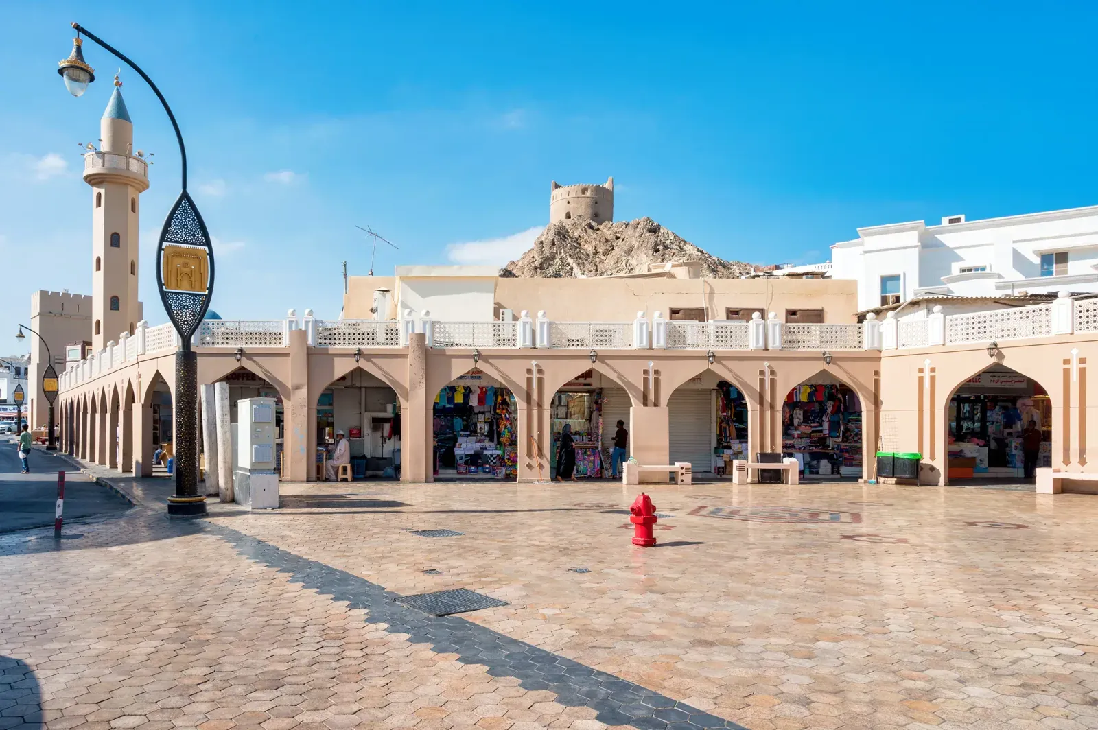 Het overdekte plein van de Mutrah Souq aan de Corniche van Muscat, met het Mutrah-fort op de heuvel erachter