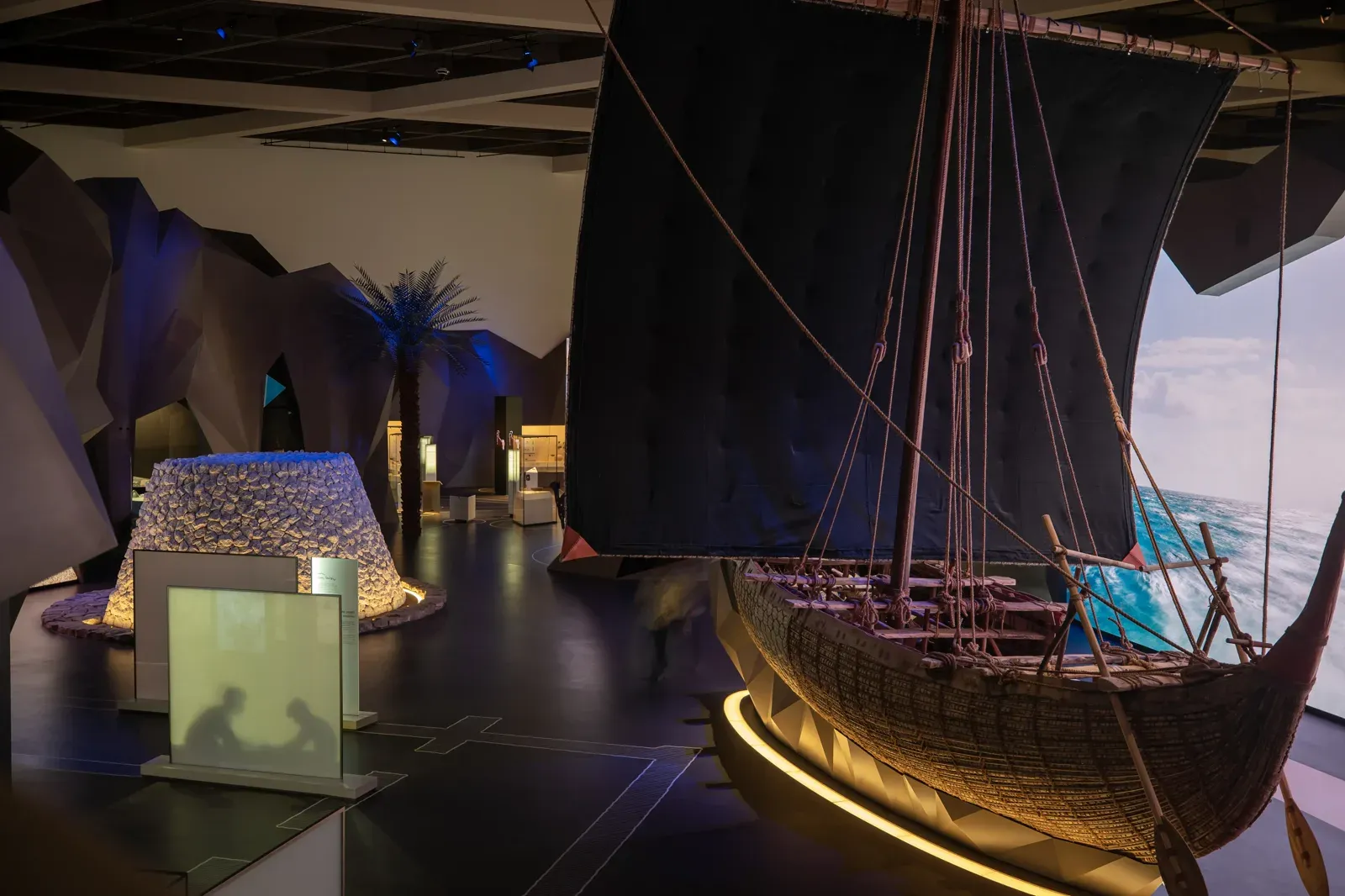 Een levensgrote traditionele dhow in een sfeervol verlichte tentoonstellingszaal van het Oman Across Ages Museum