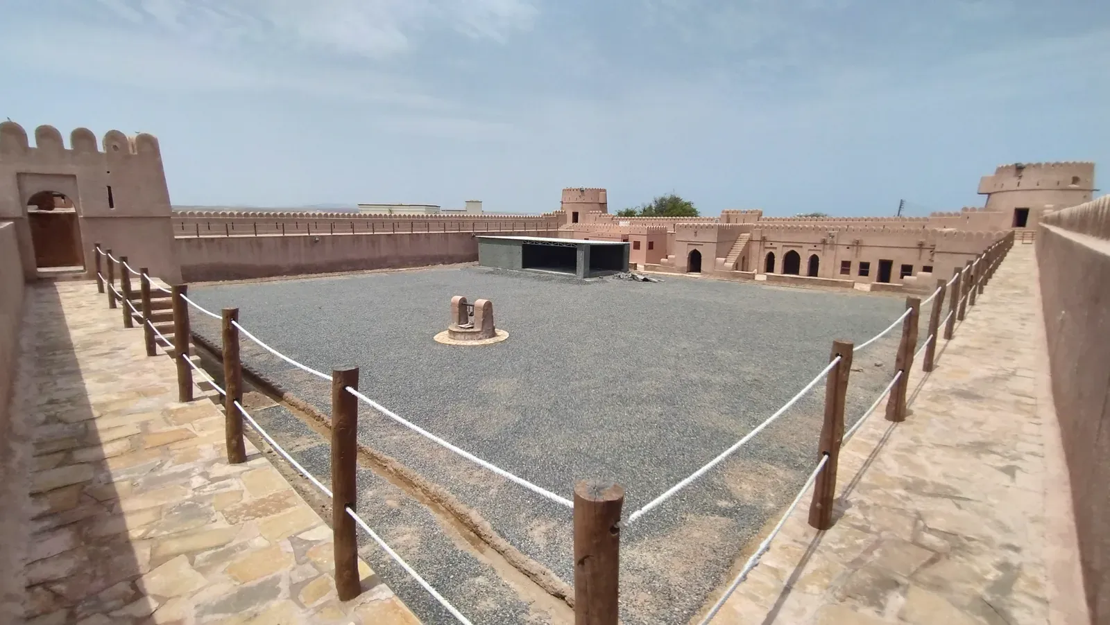 De ruime binnenplaats van Ras Al Hadd Castle met kantelen, een centrale waterput en de zandkleurige vleugels rondom