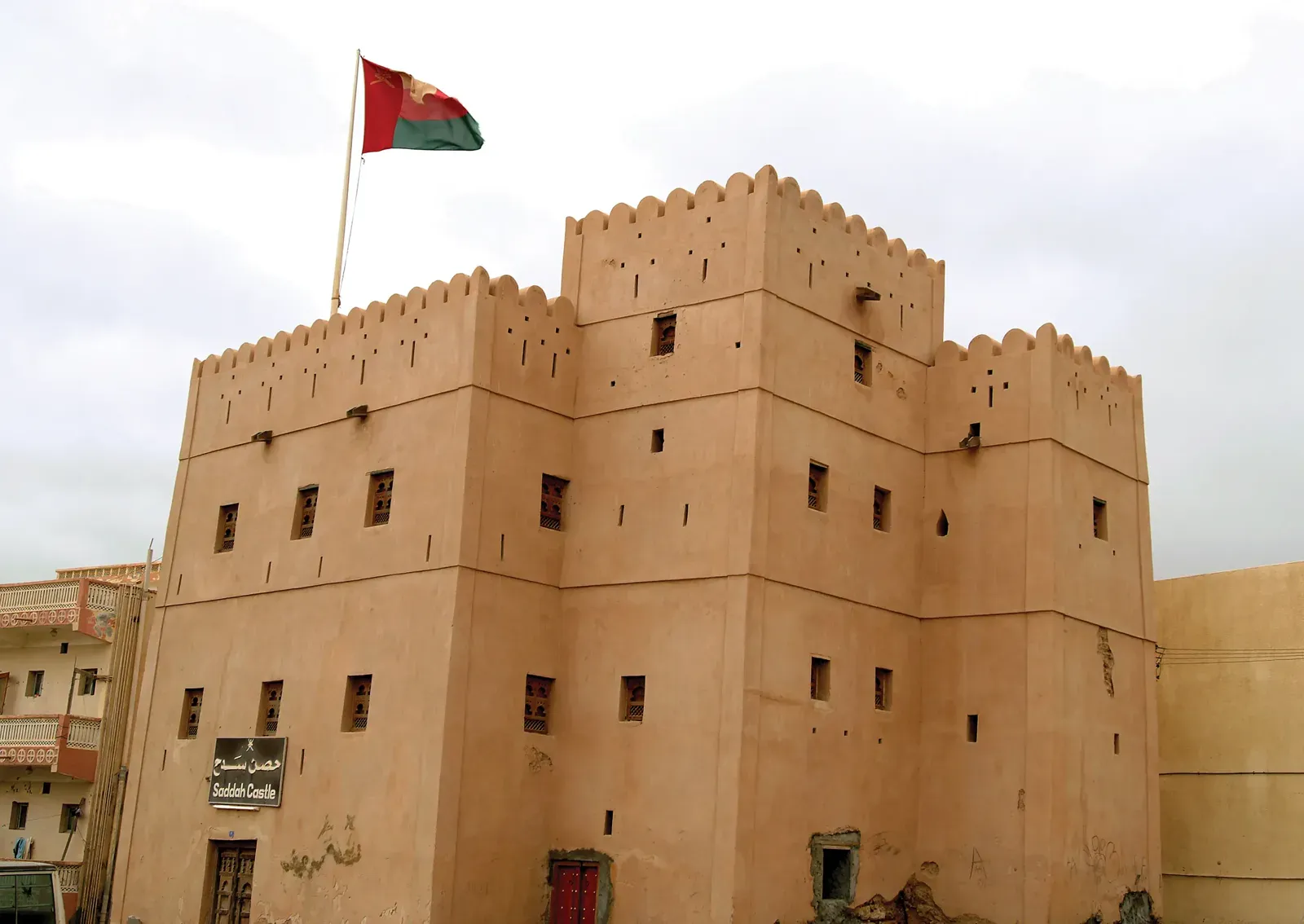 Het tanekleurige Sadah Castle met kantelen en de Omaanse vlag, de laatste oostelijke vesting aan de kust van Dhofar