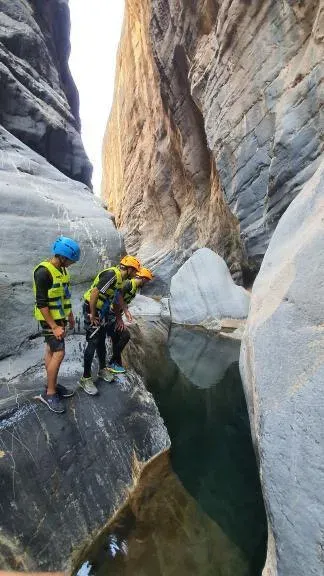 Avonturiers met helm en zwemvest klimmen door de nauwe kloof van Snake Canyon
