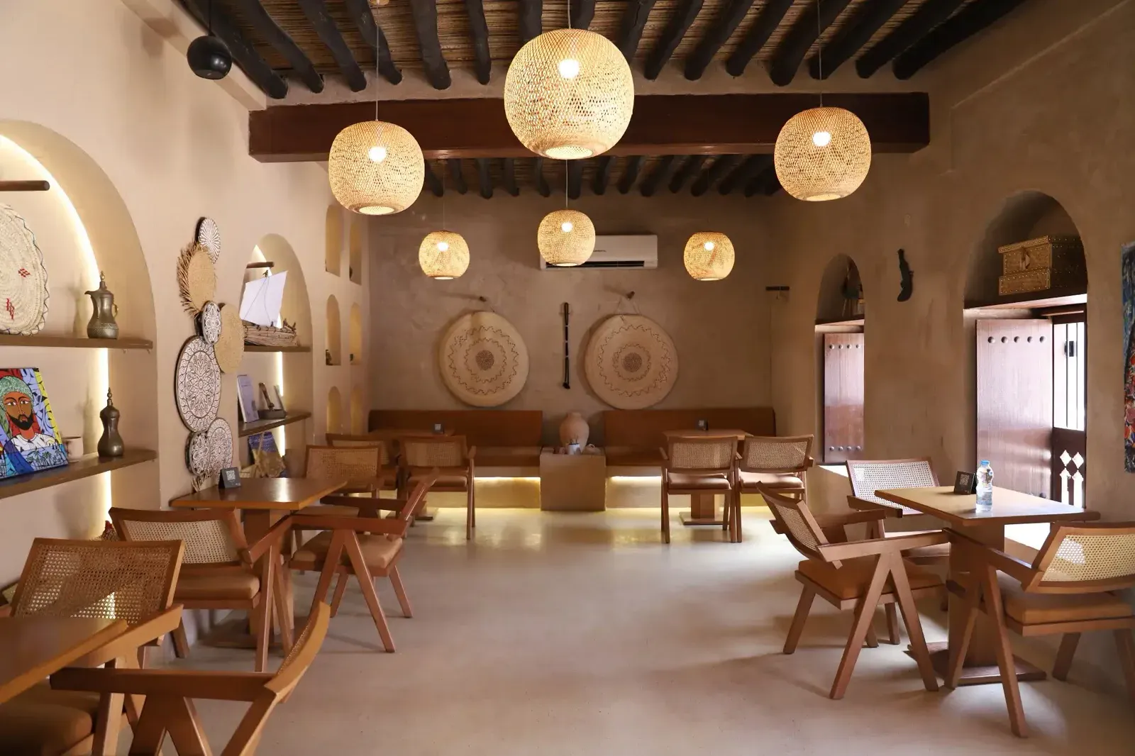 Een sfeervolle majlis in Sur Burj al Khamis met rotan meubels, rieten hanglampen en Omaans handwerk aan de wanden