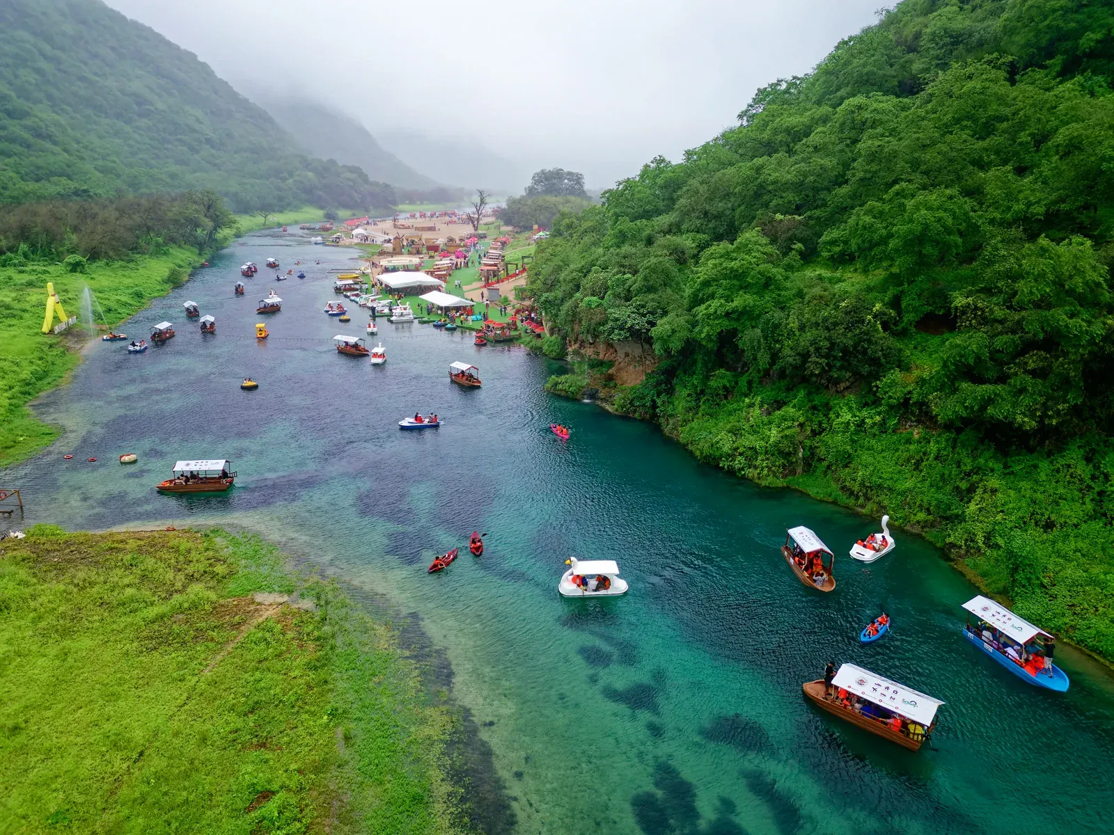 Luchtfoto van Wadi Darbat met traditionele bootjes op het turquoise water tussen groene moessonheuvels