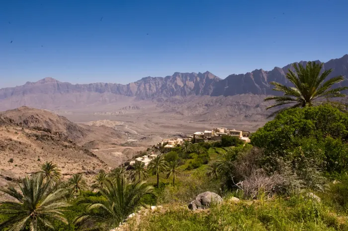 Het bergdorp Wakan hoog in het Hajar-gebergte, omringd door groene terrassen en palmen met uitzicht over de bergvallei