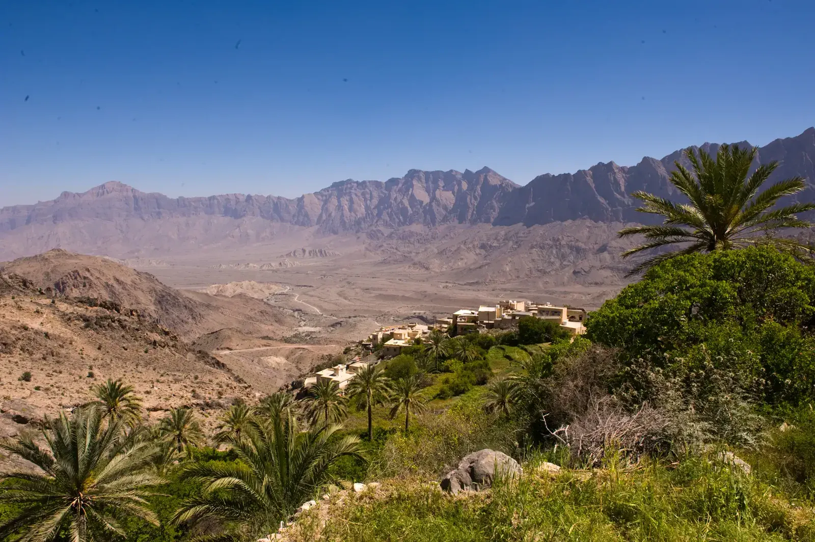 Het bergdorp Wakan hoog in het Hajar-gebergte, omringd door groene terrassen en palmen met uitzicht over de bergvallei