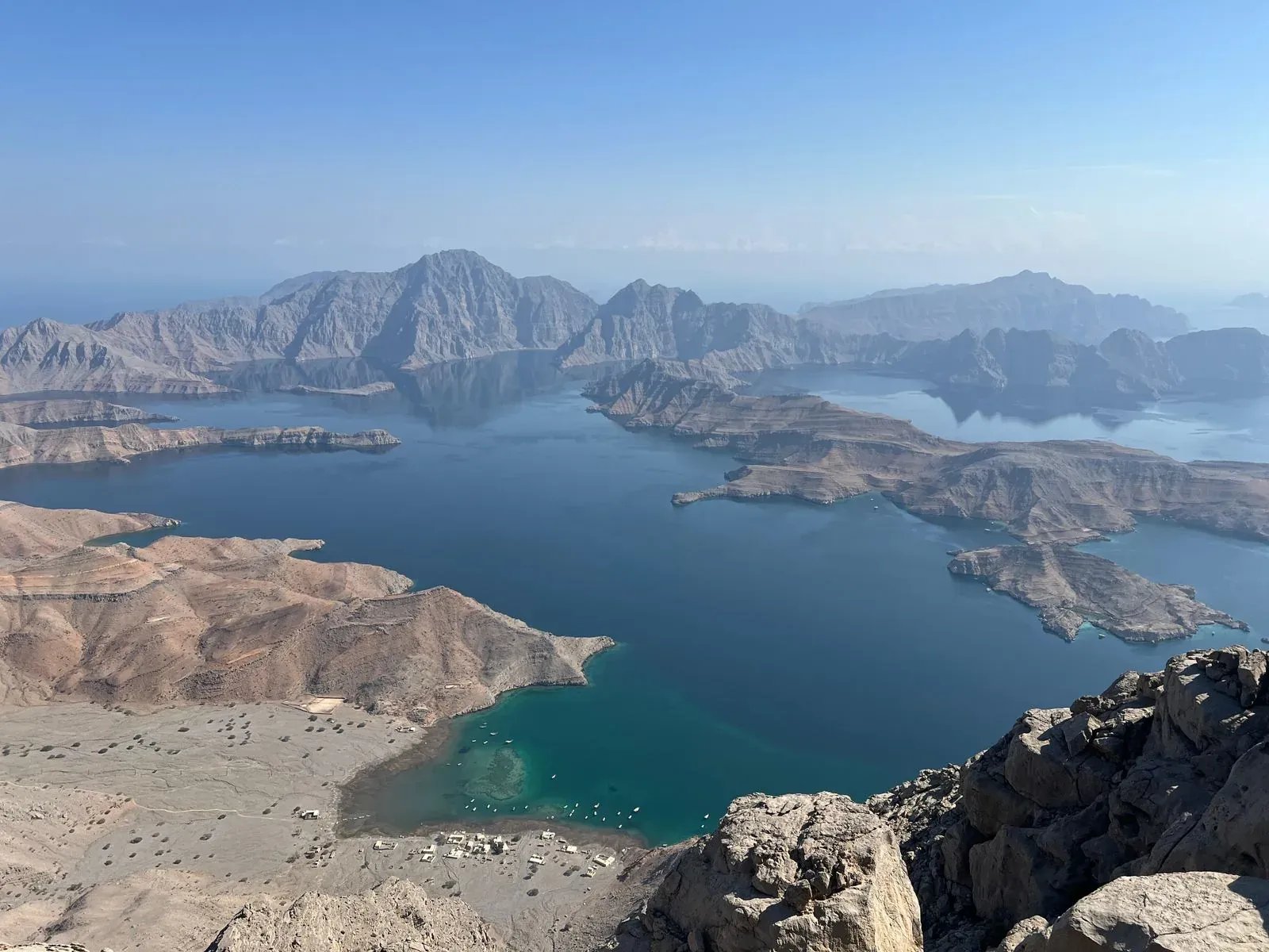 Weids uitzicht vanaf een bergkam over de diepblauwe fjorden en kale bergruggen van Musandam